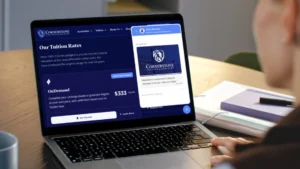 Laptop screen showing Cornerstone College tuition page with the 'Our Tuition Rates' heading on a dark blue layout.