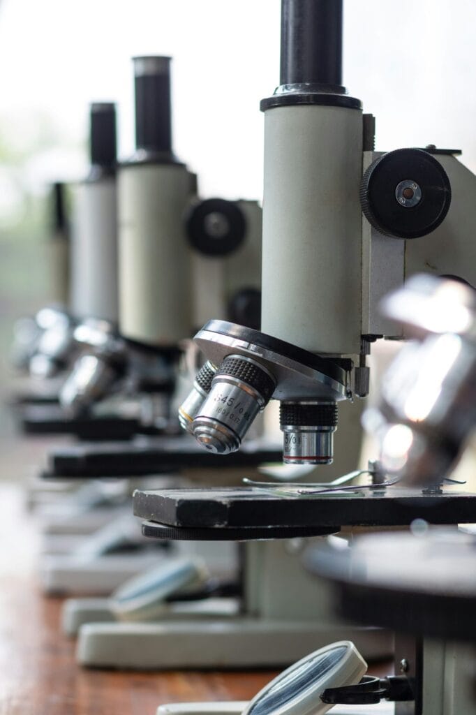 Row of compound microscopes in a lab, close-up on the objective lenses and stage for viewing slides
